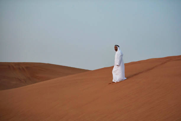 Arabic man walking in the desert in the morning, Dubai, UAE.